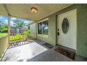 View of the covered front porch with concrete flooring, and a welcome mat near the white front door at 8537 93Rd Ave, Seminole, FL 33777
