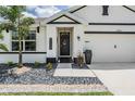 Close up of a beautifully landscaped front porch with decorative black front door, and rock garden at 9028 Forge Breeze Loop, Wesley Chapel, FL 33545