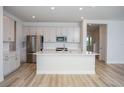 Bright open-concept kitchen boasting gray cabinets, stainless appliances, a quartz island, and light wood-look floors at 10036 Surrey Rose Dr, San Antonio, FL 33576