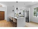 Modern white kitchen with stainless steel appliances, pendant lighting and a large island with bar seating at 1500 49Th N St, St Petersburg, FL 33710