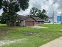 A single-story home with brown trim sits on a spacious lot with ample green space, near a sidewalk at 17004 State Road 54, Lutz, FL 33558