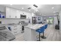Modern kitchen with white cabinets, stainless steel appliances, marble countertop island and stylish blue bar stools at 1701 Pinehurst Rd # 33E, Dunedin, FL 34698