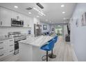 Modern kitchen with white cabinets, stainless steel appliances, marble countertop island and stylish blue bar stools at 1701 Pinehurst Rd # 33E, Dunedin, FL 34698
