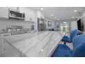 Bright kitchen featuring white cabinets, stainless steel appliances, and a marble countertop island with seating at 1701 Pinehurst Rd # 33E, Dunedin, FL 34698