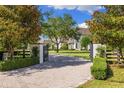 Elegant gated entrance leading to a beautiful home with well-manicured landscaping and a brick driveway at 18521 Wayne Rd, Odessa, FL 33556