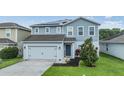 Charming two-story blue house with an attached garage, featuring solar panels and a neatly landscaped front yard at 2073 Branding Iron Way, New Port Richey, FL 34655