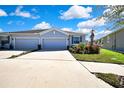 View of a single-story home with a wide driveway, and three-car garage under a blue sky at 31105 Mango Fade Way, San Antonio, FL 33576