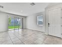 A bright, open living room featuring neutral tile floors, white walls, and a sliding glass door at 31105 Mango Fade Way, San Antonio, FL 33576