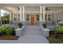 Inviting front porch with gray painted floors, white pillars, ceiling fans, stylish railing, and manicured landscaping at 3811 N Arlington Ave, Tampa, FL 33603