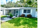 Inviting single-story home with lush lawn, white rock landscape features, and screened-in porch at 411 Locklie St, Dunedin, FL 34698
