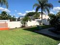 Large grassy backyard features a patio, a fence, and lush green trees and landscaping at 5139 Corvette Dr, Tampa, FL 33624