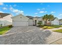 Charming home boasts a three-car garage and meticulously laid paver driveway with lush front lawn at 6035 Nikki Ln, Odessa, FL 33556