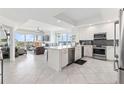 Open-concept kitchen with white cabinets, quartz countertops, stainless steel appliances and spacious island at 706 Bayway Blvd # 503, Clearwater, FL 33767