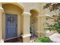 Charming entrance with colorful floral wreath on blue door, decorative columns and paver walkway at 9206 River Rock Ln, Riverview, FL 33578