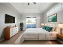 Bright bedroom features a tray ceiling, light gray walls, and sliding glass doors to the outdoor patio at 10101 Paddock Oaks Dr, Riverview, FL 33569