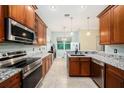 Well-equipped kitchen with stainless steel appliances, granite countertops, and wood cabinetry at 11220 Paradise Pointe Way, New Port Richey, FL 34654