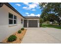 Well-maintained home featuring a concrete driveway leading to a gray garage door, and manicured landscaping at 1707 Solon Ave, Dunedin, FL 34698