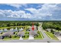 Aerial view of a gray home next to a pond and lush woods, showcasing its desirable location at 18527 Cortes Creek Blvd, Spring Hill, FL 34610