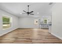 Living room features wood-look floors, neutral walls, large windows, and modern ceiling fan at 19275 Wildwood Dr, Brooksville, FL 34601