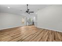 Bright living room with modern wood floors, ceiling fan, and views of the kitchen at 19275 Wildwood Dr, Brooksville, FL 34601