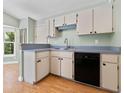 Efficient kitchen featuring wood floors, white cabinets, and black appliances at 2068 Diane Ave, Palm Harbor, FL 34683