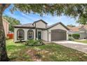 Charming home exterior with a well-kept lawn, two-car garage and lush greenery, shaded by a mature tree at 22824 Marsh Wren Dr, Land O Lakes, FL 34639
