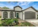 Charming home featuring a well-kept lawn, arched windows, and a two-car garage at 22824 Marsh Wren Dr, Land O Lakes, FL 34639