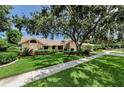 Charming single-story home with lush landscaping and a concrete walkway underneath a large tree at 2455 Anthony Ave, Clearwater, FL 33759