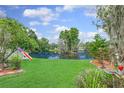Tranquil backyard featuring a serene lake view, lush greenery, and well-maintained lawn at 3026 Cedaridge Dr, Tampa, FL 33618