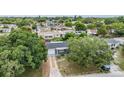 Aerial view of a gray home with a driveway, nestled among lush trees in a quiet neighborhood at 3625 Oakhurst Dr, Holiday, FL 34691