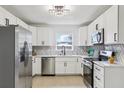 Bright kitchen with white cabinetry, stainless steel appliances, modern lighting, and stylish backsplash at 6 N Orion Ave, Clearwater, FL 33765