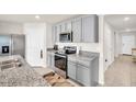 This spacious kitchen features stainless steel appliances, granite countertops, and grey cabinets at 7774 Sail Clover Ln, Zephyrhills, FL 33540