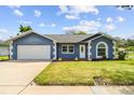 Charming single-story home featuring a well-manicured lawn, blue exterior, and a two-car garage at 8823 Aruba Ln, Port Richey, FL 34668