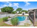 Inviting backyard pool with stone surround and lush landscaping adjacent to the enclosed lanai at 901 Strawberry Ln, Brandon, FL 33511