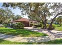 Well-maintained home featuring a brick driveway, mature trees, and a two-car garage at 13747 Forest Ridge Ct, Hudson, FL 34667