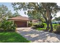 Well-maintained home with a brick driveway, two-car garage, and mature shade trees at 13747 Forest Ridge Ct, Hudson, FL 34667