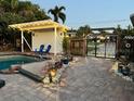 Outdoor pool area featuring a covered patio with bistro lights, seating, and paver deck at 3012 Grand View Ave, Clearwater, FL 33759