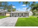 Charming single-story home with gray exterior, well-manicured lawn, and brick driveway under sunny skies at 3135 W Varn Ave, Tampa, FL 33611