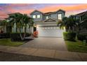 Striking two-story home at twilight features a paved driveway, two-car garage, and tropical landscaping at 315 Blackrock Ln, Apollo Beach, FL 33572