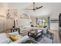 Bright living room with a white leather sectional sofa, modern ceiling fan, and view of screened lanai at 37147 Foxrun Pl, Zephyrhills, FL 33542
