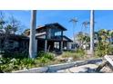 Home's exterior elevation displaying a modern design, expansive windows, mature landscaping, and some visible damage at 720 Boca Ciega Isle Dr, St Pete Beach, FL 33706