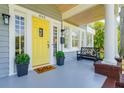 Inviting front porch with bright yellow door, bench seating, potted plants, and brick foundation at 842 S Boulevard, Tampa, FL 33606