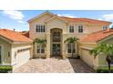 Well-maintained home featuring a brick driveway, three-car garage, and tropical landscaping at 8476 Dunham Station Dr, Tampa, FL 33647