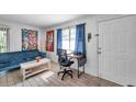Bright living room showcasing wood-look tile flooring, comfortable seating, and a desk near a window at 10195 Sailwinds N Blvd # 208, Largo, FL 33773