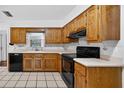 Traditional kitchen with wooden cabinets, black appliances, and tile flooring at 11001 Ridgedale Rd, Temple Terrace, FL 33617