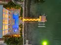 Overhead view of waterfront home showcasing sparkling pool, lit dock, and waterfront access at 11260 7Th E St, Treasure Island, FL 33706