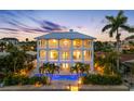 Beautiful back elevation of the home at dusk with a sparkling pool and tropical landscaping at 11260 7Th E St, Treasure Island, FL 33706