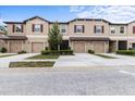 Street view of townhomes with attached garages and tan exteriors showcasing inviting curb appeal with a blue sky at 11916 Castine St, New Port Richey, FL 34654