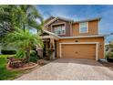 Inviting two-story home with a brick driveway, two-car garage, and beautiful landscaping at 1601 Fox Grape Loop, Lutz, FL 33558