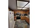 Kitchen with white appliances, wood cabinets, and accent rug at 2685 Sabal Springs Cir # 202, Clearwater, FL 33761